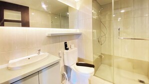Une salle de bain moderne avec une douche à parois de verre, un lavabo blanc et des toilettes.