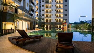 A hotel pool area with lounge chairs and a water feature.