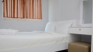 A neatly made bed with white linens, a brown ottoman, a white dresser, and a mirror above it. - Unique And Fresh 1Br Signature Park Grande Apartment (Jakarta)