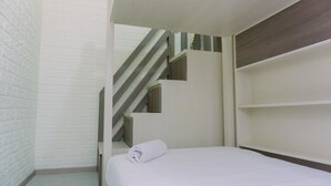 Une chambre d’hôtel avec un lit, un escalier en bois et des étagères intégrées.