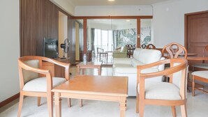 A living room with a wooden table and chairs, a sofa, and a television. - Elegant And Homey 2Br Apartment At Puri Casablanca (Jakarta)