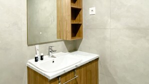 Un baño moderno con un lavamanos blanco, tocador de madera y un espejo grande.