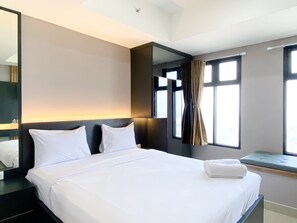 A hotel room with a large bed, a bedside table, a mirror, and a window with curtains. - Cozy Studio High Floor Pollux Chadstone Apartment (Cikarang)
