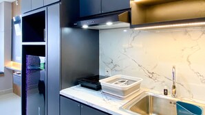 Una cocina moderna con armarios oscuros, encimera de mármol y pileta de acero inoxidable.