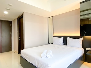 A modern hotel room with a large bed, a mirror, and a nightstand. - Cozy Studio High Floor Pollux Chadstone Apartment (Cikarang)