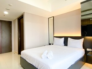 Relax in a spacious room with a large bed, a dark headboard, and a mirror above.