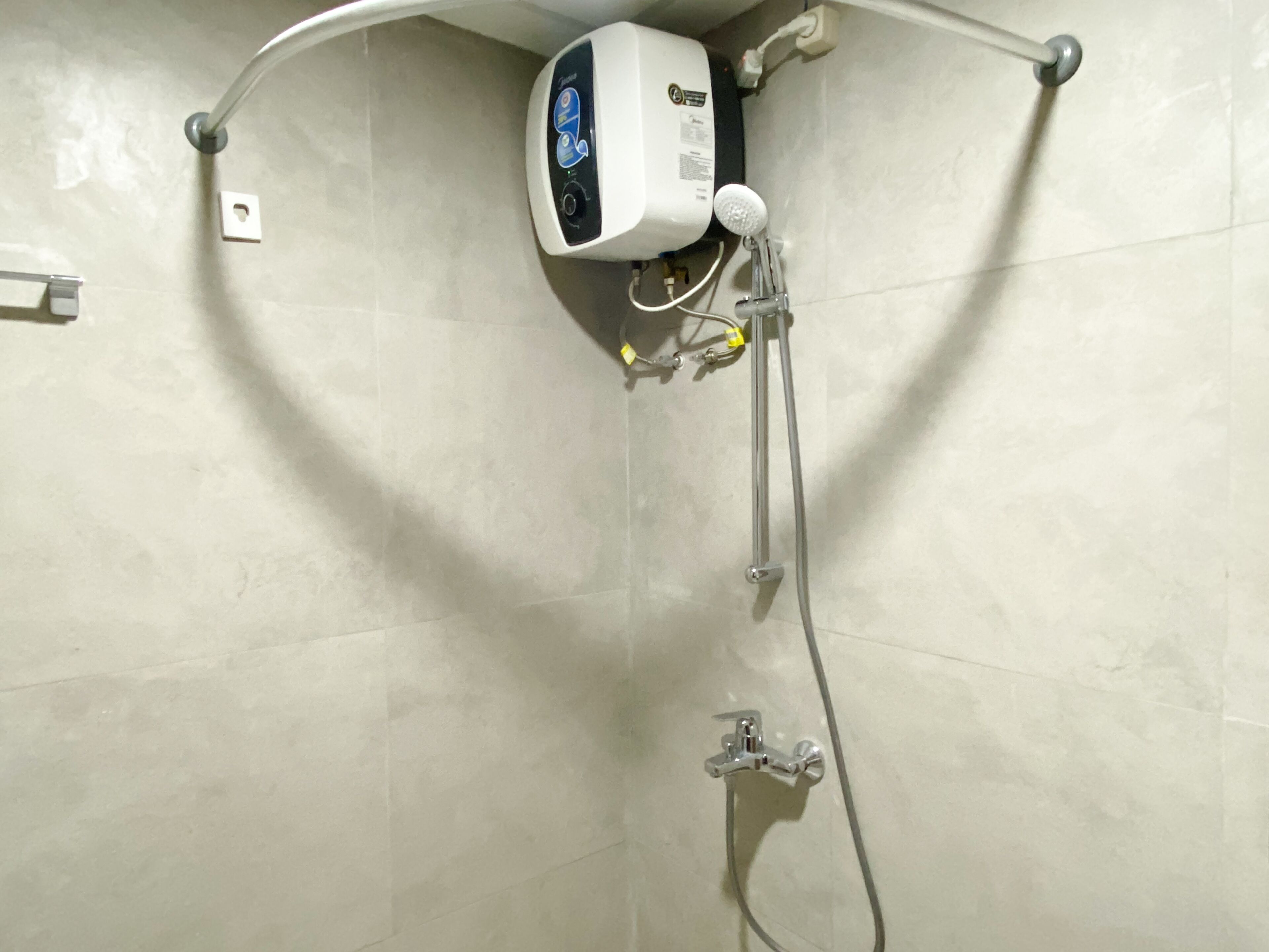 Ducha en esquina con cabezal de ducha de mano y panel de control en la pared.