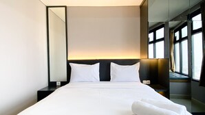 Un hotel moderno con una cama grande, una mesita de noche, un espejo y vistas a la ciudad a través de amplios ventanales.