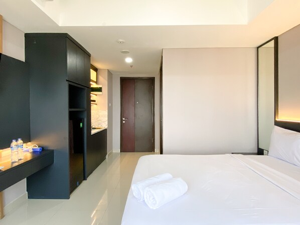 Relax in a serene space with a neatly made bed, dark wardrobe, and compact desk area.