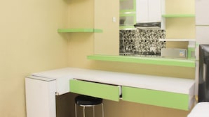 A compact kitchenette with a white countertop, green shelving, and a black stool. - Nice And Comfortable Studio At Bassura City Apartment Near Mall (Jakarta)