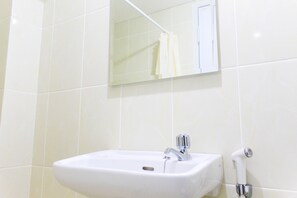 A bathroom with a white sink, a mirror, and a shower. - Comfortable And Classic Studio Apartment At M-Town Residence (Gading Serpong)
