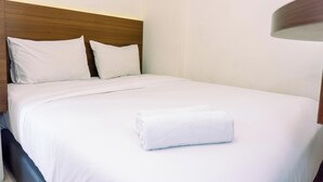 A neatly made bed with white linens and pillows, a wooden headboard, and a rolled white towel on the bed. - Cozy Stay 2Br Annora Living Apartment (Tangerang)