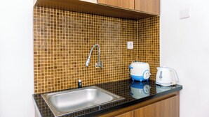 A kitchen with a tiled backsplash, a stainless steel sink, a kettle, and a toaster. - Cozy Stay 2Br Annora Living Apartment (Tangerang)