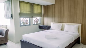 Habitación de hotel moderna con una cama grande, una mesita de noche, una silla y una ventana con vistas a flores.