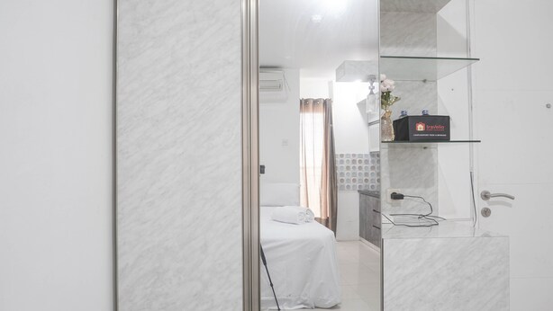 Ett hotellrum med en säng, ett badrum med en duschkabin med glasväggar och en minibar.