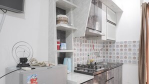Cocina compacta con estufa integrada, refrigerador y microondas. Hay armarios y una encimera con lavamanos.