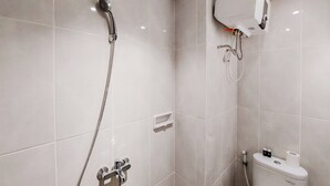 A modern bathroom with a shower, toilet, and a built-in water heater. - Homey And Comfortable Studio At Serpong Garden Apartment (Cisauk)
