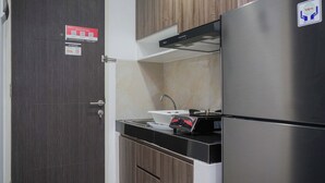 A compact kitchen with a stainless steel refrigerator, a built-in oven, and a sink. - Homey And Comfortable Studio At Serpong Garden Apartment (Cisauk)