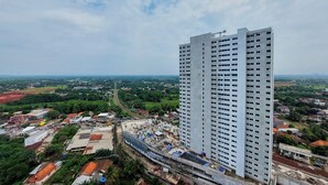 A high-rise building with a modern design, surrounded by a mix of residential and commercial buildings, and a green landscape in the background. - Homey And Comfortable Studio At Serpong Garden Apartment (Cisauk)
