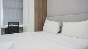 A hotel room with a large bed, a wooden accent wall, and a window with a view. - Homey And Comfortable Studio At Serpong Garden Apartment (Cisauk)