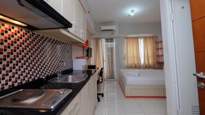 Une chambre d’hôtel compacte comprenant une kitchenette, un lit et une salle de bain.