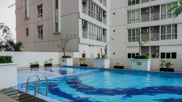 Une piscine intérieure à l’eau claire, entourée d’un bâtiment doté de nombreux balcons et agrémenté de plantes en pot.