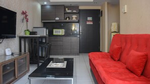 A compact living space with a kitchenette, a sofa, a coffee table, and a television. - Cozy And Elegant 1Br At The Wave Apartment Kuningan (Jakarta)