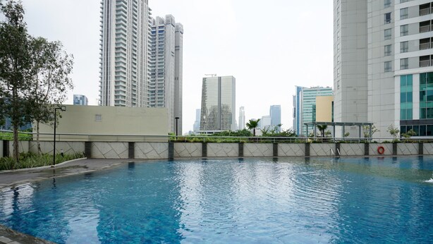 A swimming pool with a cityscape in the background. - Cozy And Elegant 1Br At The Wave Apartment Kuningan (Jakarta)