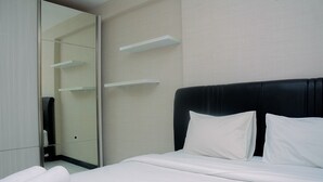 A neatly made bed with white linens, a black headboard, and a rolled white towel on the side. - Cozy And Elegant 1Br At The Wave Apartment Kuningan (Jakarta)