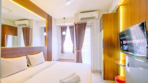 Una habitación de hotel con una cama grande, televisión, aire acondicionado y una ventana con cortinas.