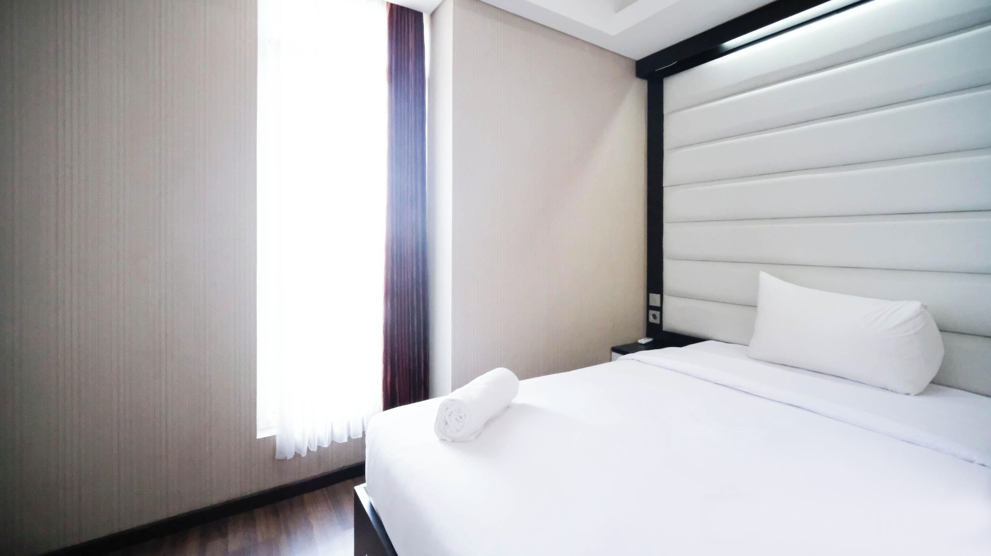Une chambre d’hôtel avec un lit, une table de chevet et une fenêtre avec des rideaux.