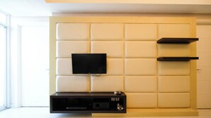 Ein modernes Wohnzimmer mit großem Wand-Fernseher, eingebauten Regalen und einem Flachbildfernseher auf einer Konsole.