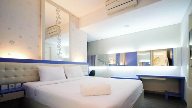 Ein Hotelzimmer mit einem großen Bett, einem Schreibtisch und einem Spiegel.