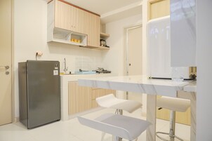 A modern kitchen with a built-in refrigerator, white bar stools, and wooden cabinets.