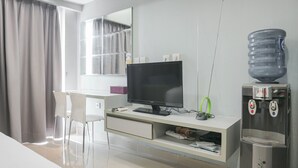 Een moderne hotelkamer met een bureau, een flatscreen televisie, een waterdispenser en een grote spiegel.