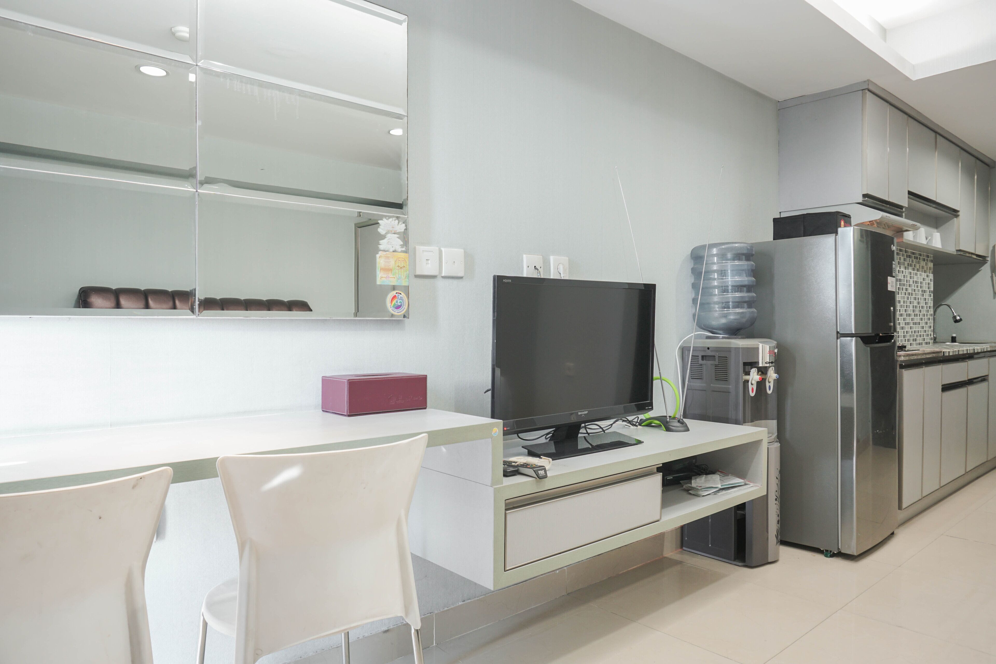 Una cocina moderna con refrigerador empotrado, televisor de pantalla plana y dispensador de agua.