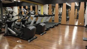 A gym with multiple treadmills and exercise equipment, wooden flooring, and mirrors on the walls.