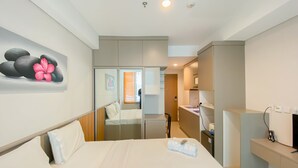 Une chambre d’hôtel moderne, équipée d’un lit, d’un bureau, d’un miroir et ornée d’un tableau représentant des pierres et des fleurs sur le mur.