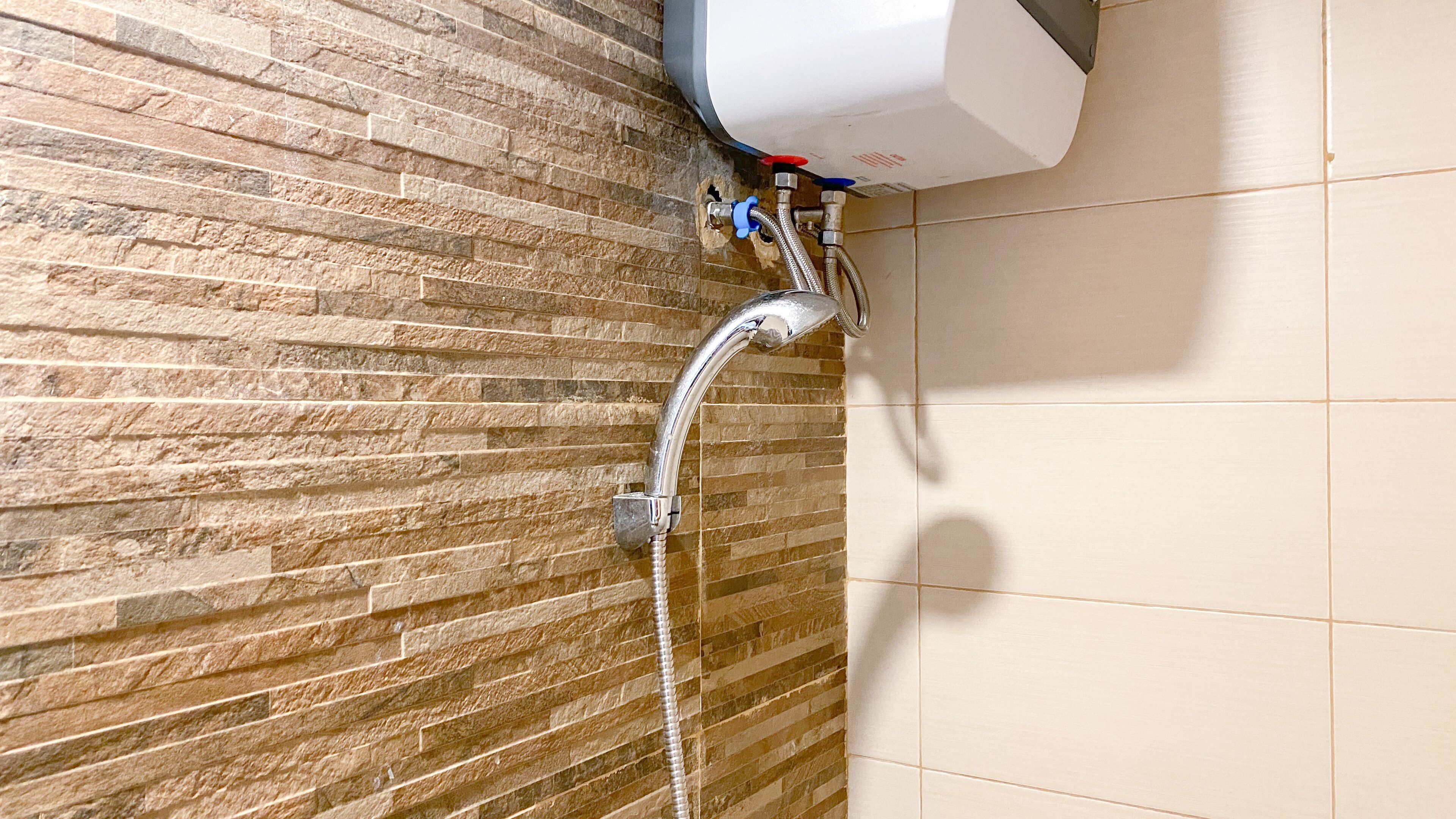 A shower area with a stone wall and a tiled floor.