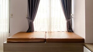 Een kamer met een raam, gordijnen en een bed.