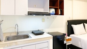 A compact kitchenette with a sink, a small refrigerator, and a microwave. - Homey And Simply Look Studio Meikarta Apartment (Cikarang)