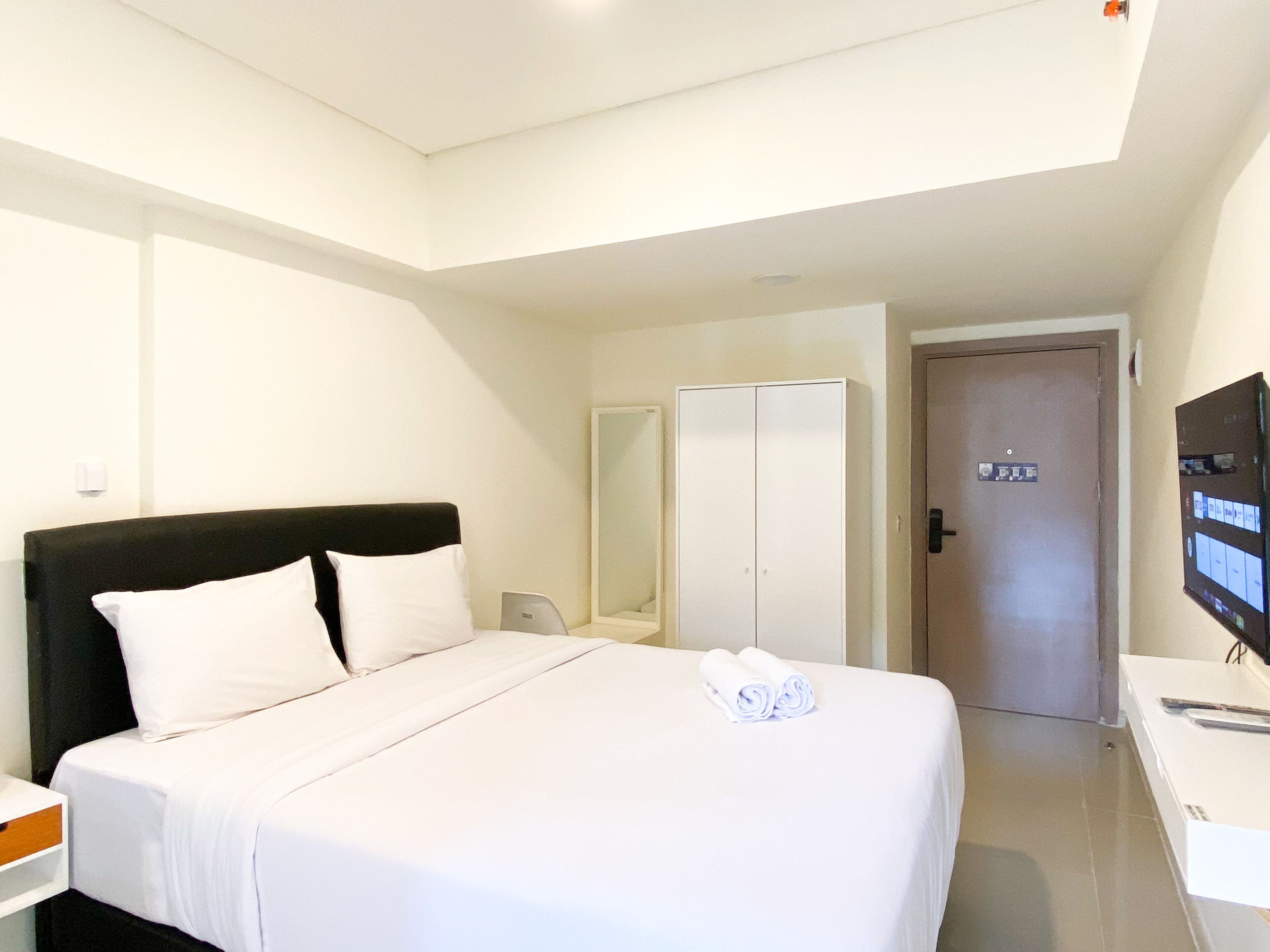 A hotel room with a bed, a TV, a wardrobe, and a door.