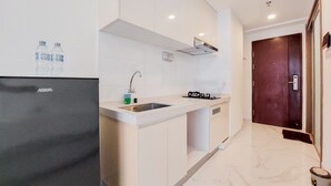 A modern kitchen with a built-in sink, a stove, and a refrigerator. - Good Deal And Comfortable Studio At Sky House Bsd Apartment (Pagedangan)