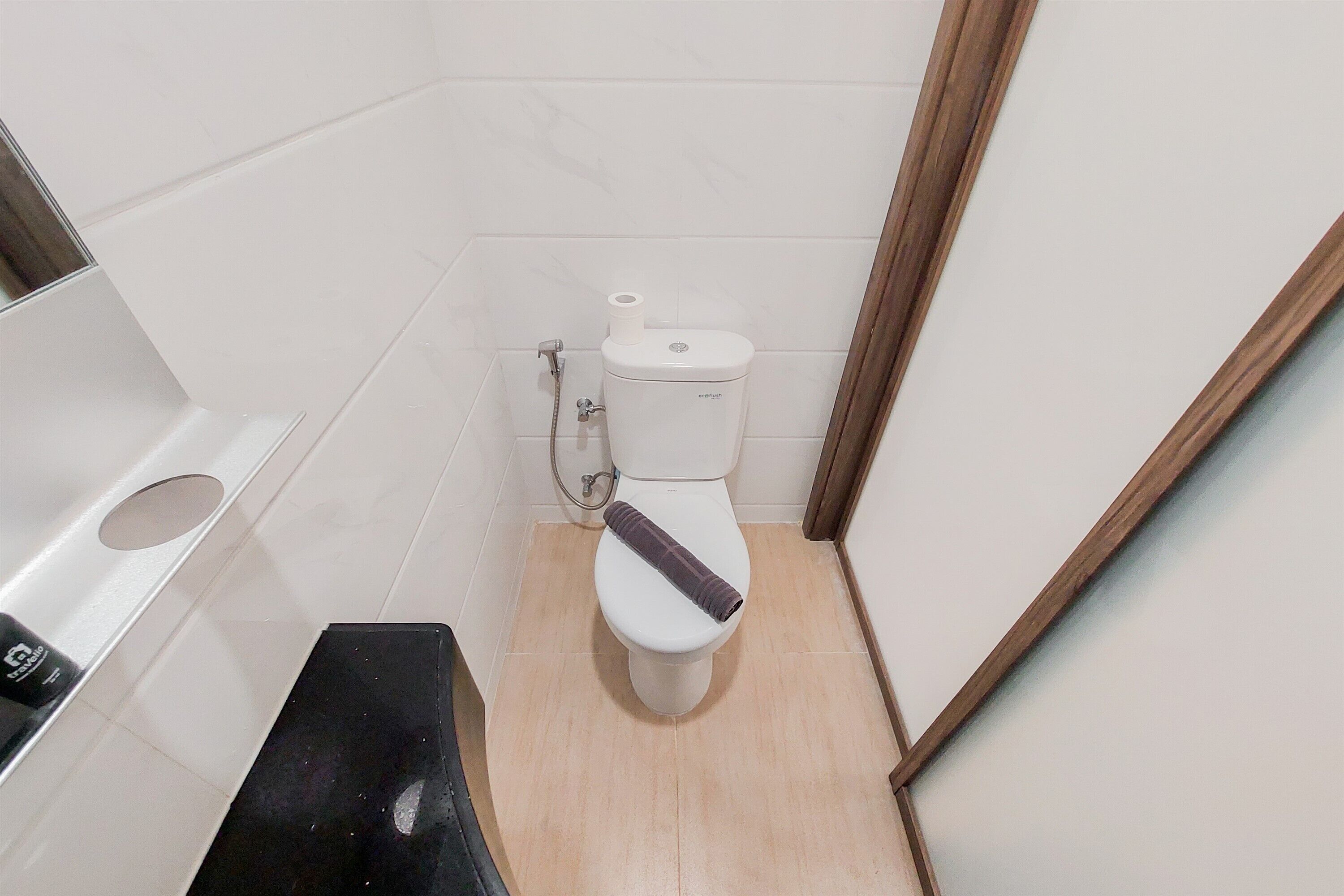 A small, compact bathroom with a white toilet, a black trash bin, and a white sink.