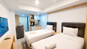 Une chambre d’hôtel avec deux lits, une petite kitchenette, une télévision et un bureau.