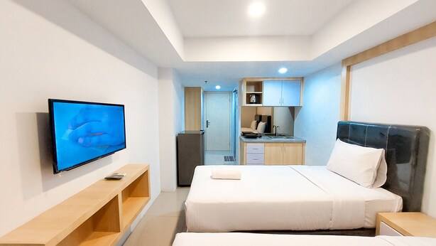 Une chambre d’hôtel comprenant un lit, des tables de chevet, une télévision, une petite kitchenette et un réfrigérateur.