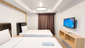 Une chambre d’hôtel avec deux lits, un téléviseur à écran plat, une étagère en bois et un luminaire au plafond.