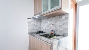 A compact kitchen with a sink, a faucet, and a soap dispenser. - Cozy Living And Homey Studio Room Cinere Resort Apartment (Depok)