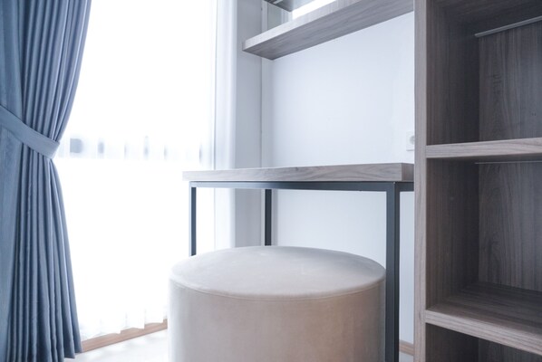 Une pièce comprenant un pouf rond, une table en bois et une armoire avec des étagères ouvertes.