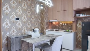 Een moderne keuken met een marmeren aanrecht, houten keukenkastjes en behang met een patroon.